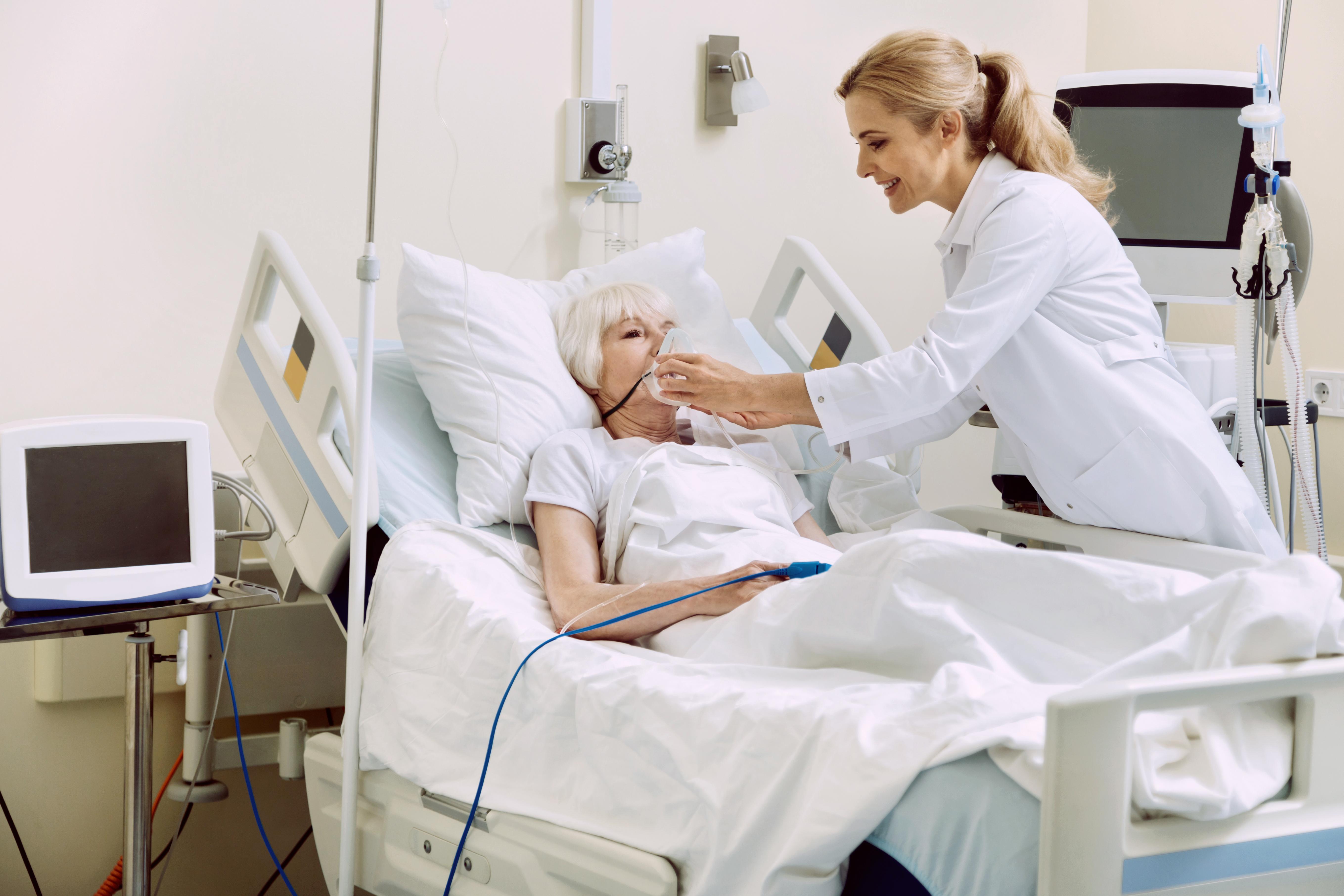 doctor helping patient in hospital bed image